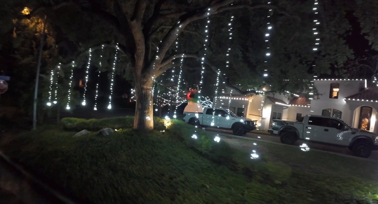 Cascading light strands hanging from a large tree over a front lawn