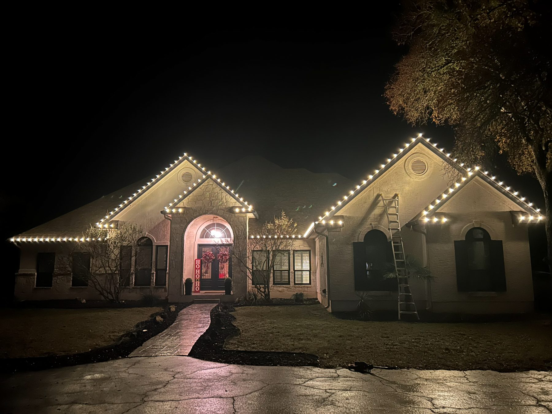 Single-story stone home outlined in warm white C9 lights along every gable